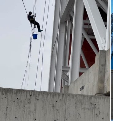 Rope-access cleaner descending a white commercial building